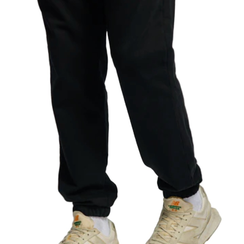 Black pants worn with beige sneakers on a light white background