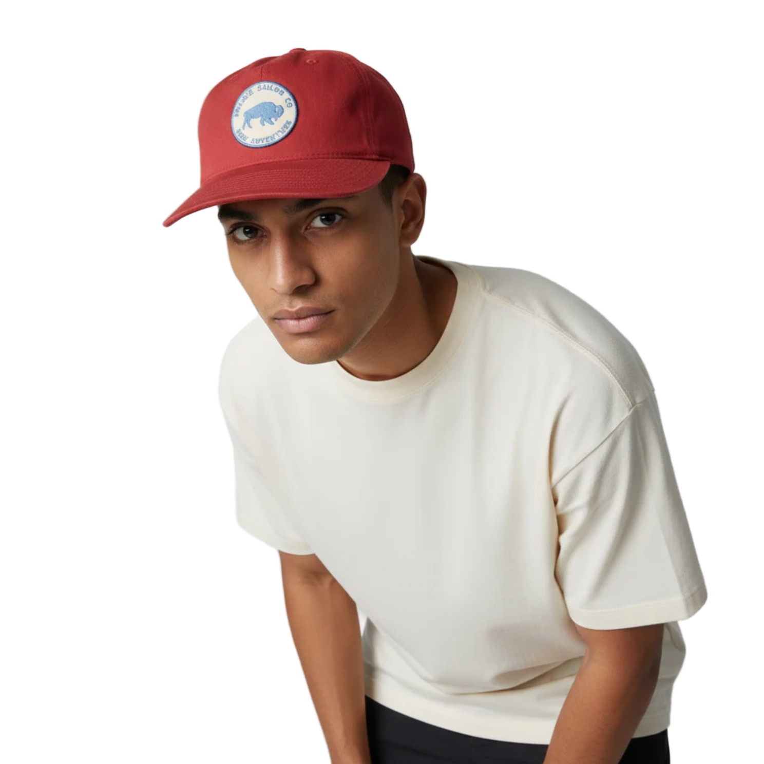 Person wearing a red cap with a logo and a white t-shirt on a white background