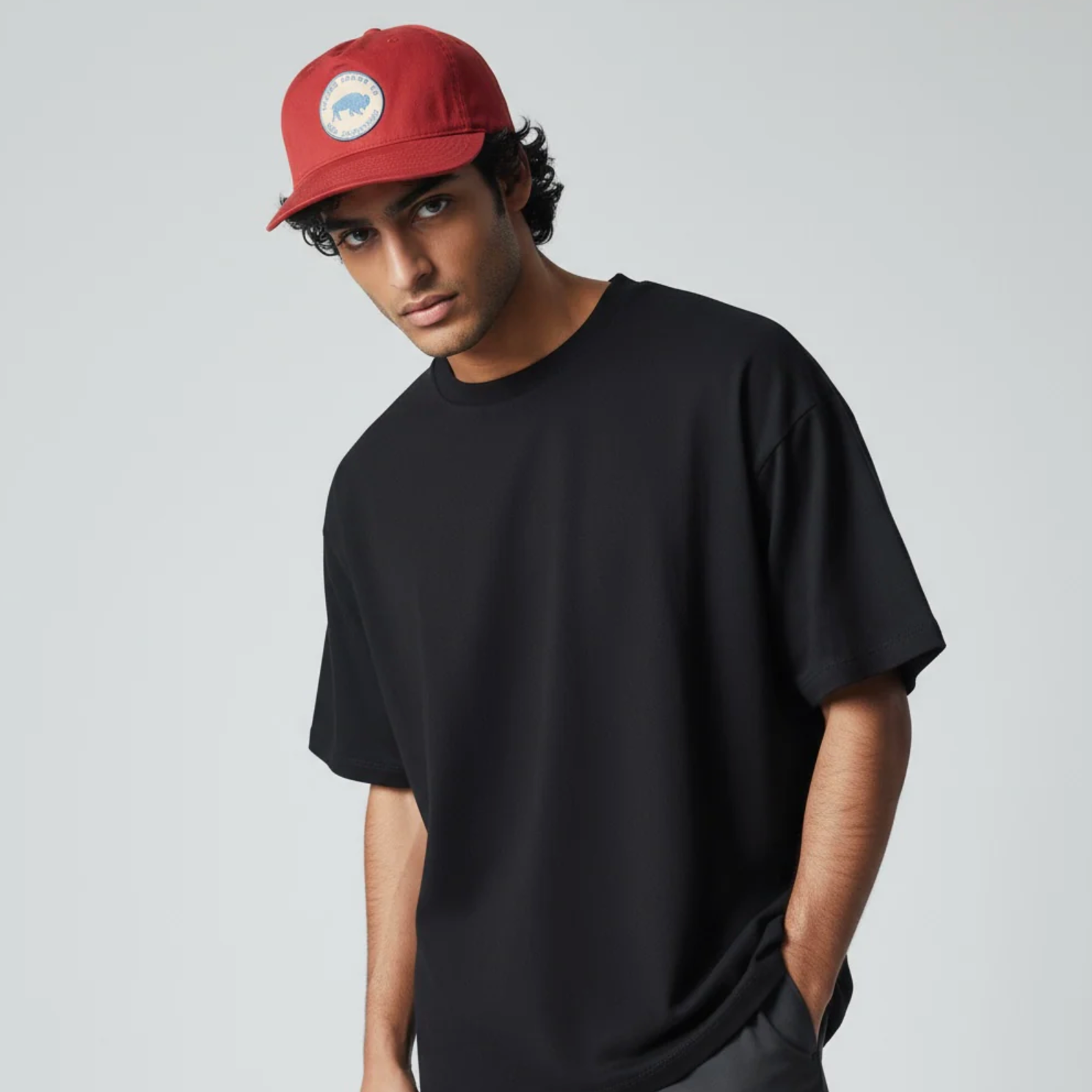Person wearing a black t-shirt and red cap on a plain background