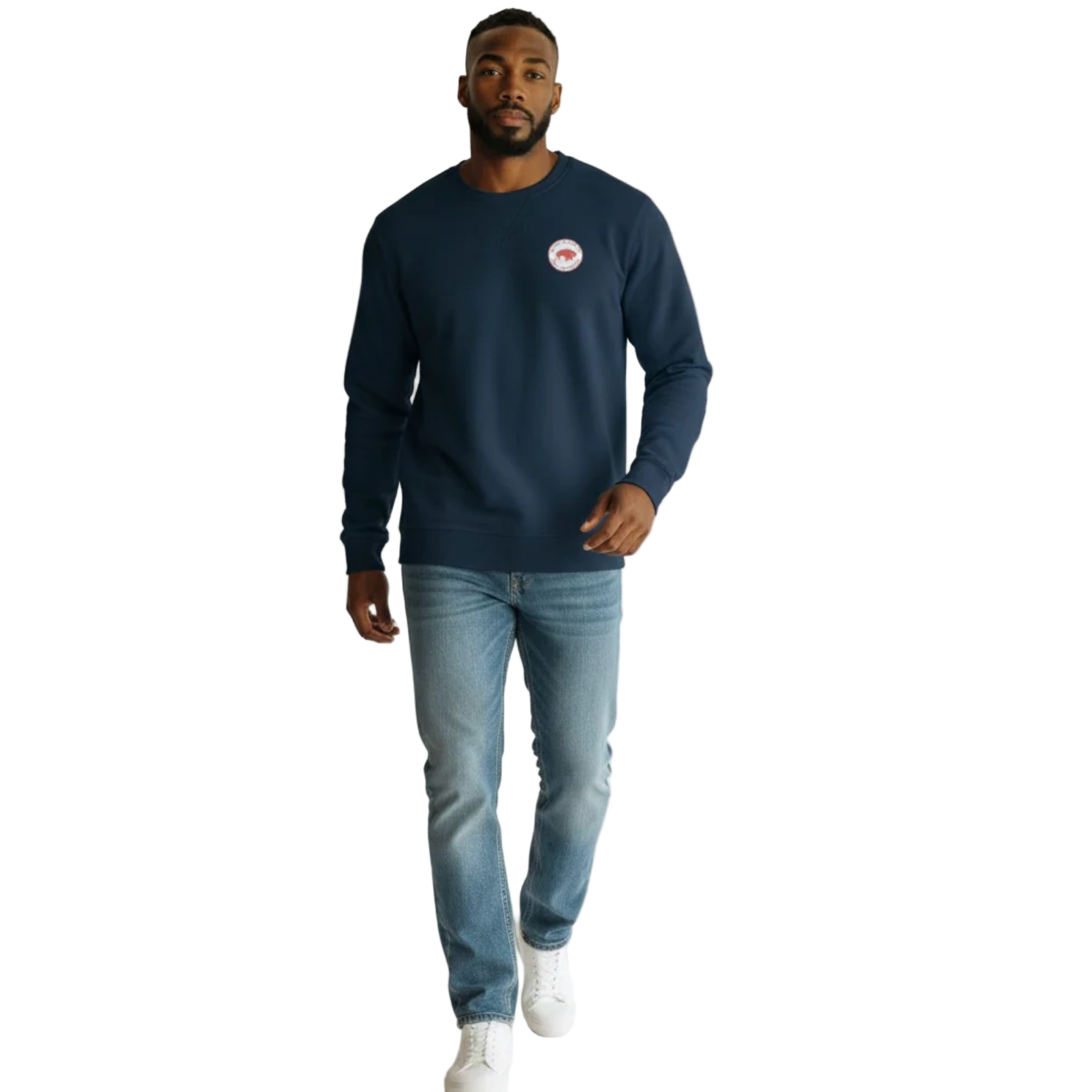 Man wearing a navy blue sweatshirt with a logo and light blue jeans on a white background