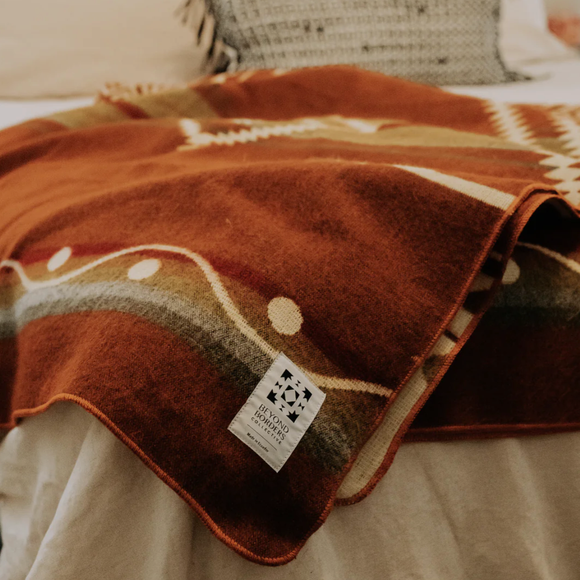 Brown patterned blanket with a label on a bed