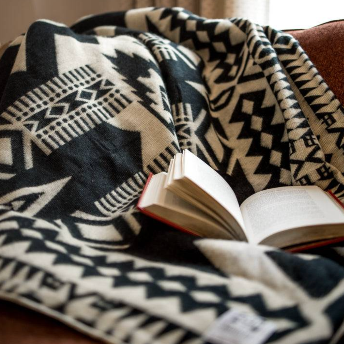 Patterned blanket draped over a surface with an open book underneath