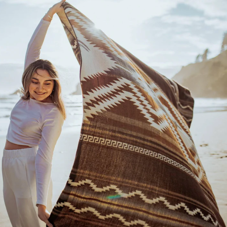 Woman holding a large patterned fabric on a beach