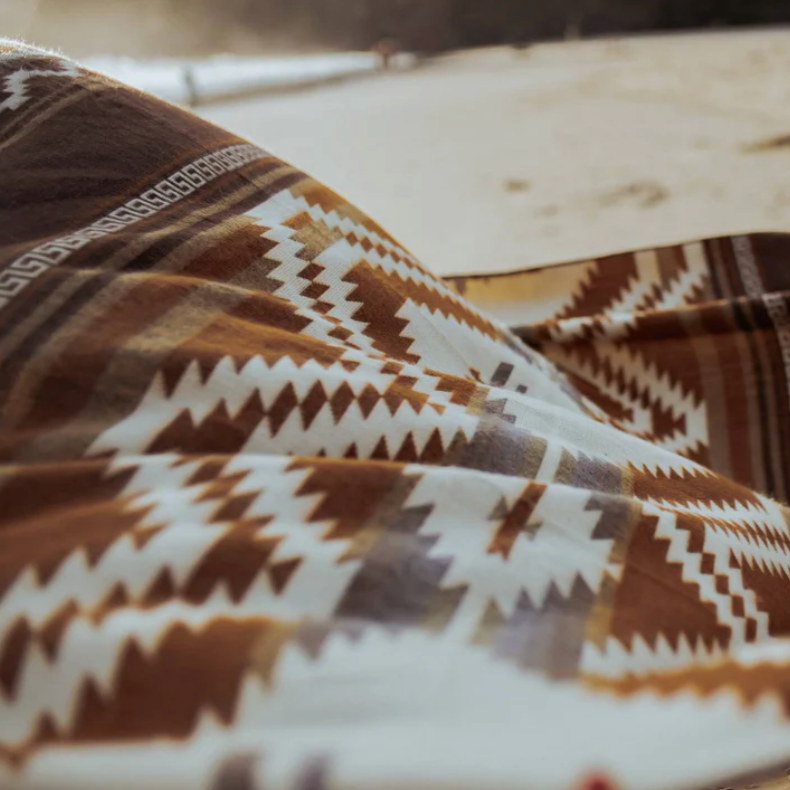 Close-up of a patterned fabric with brown and white colors, possibly on a wooden surface.