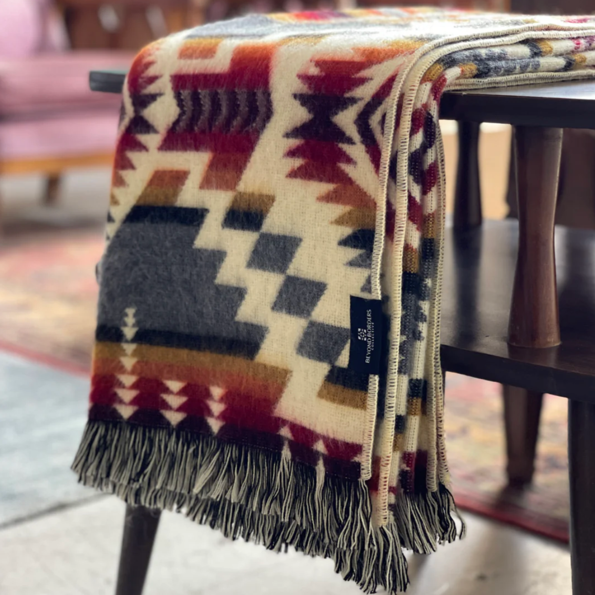Patterned blanket draped over a chair with a blurred background