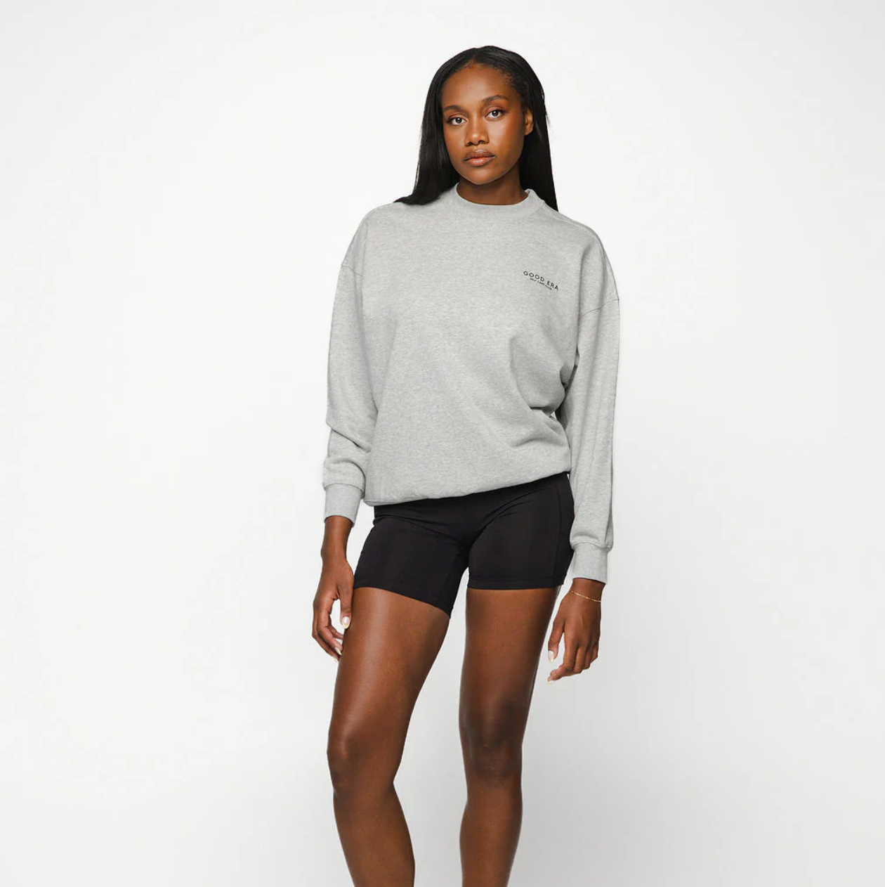 Person wearing a gray sweatshirt and black shorts on a white background