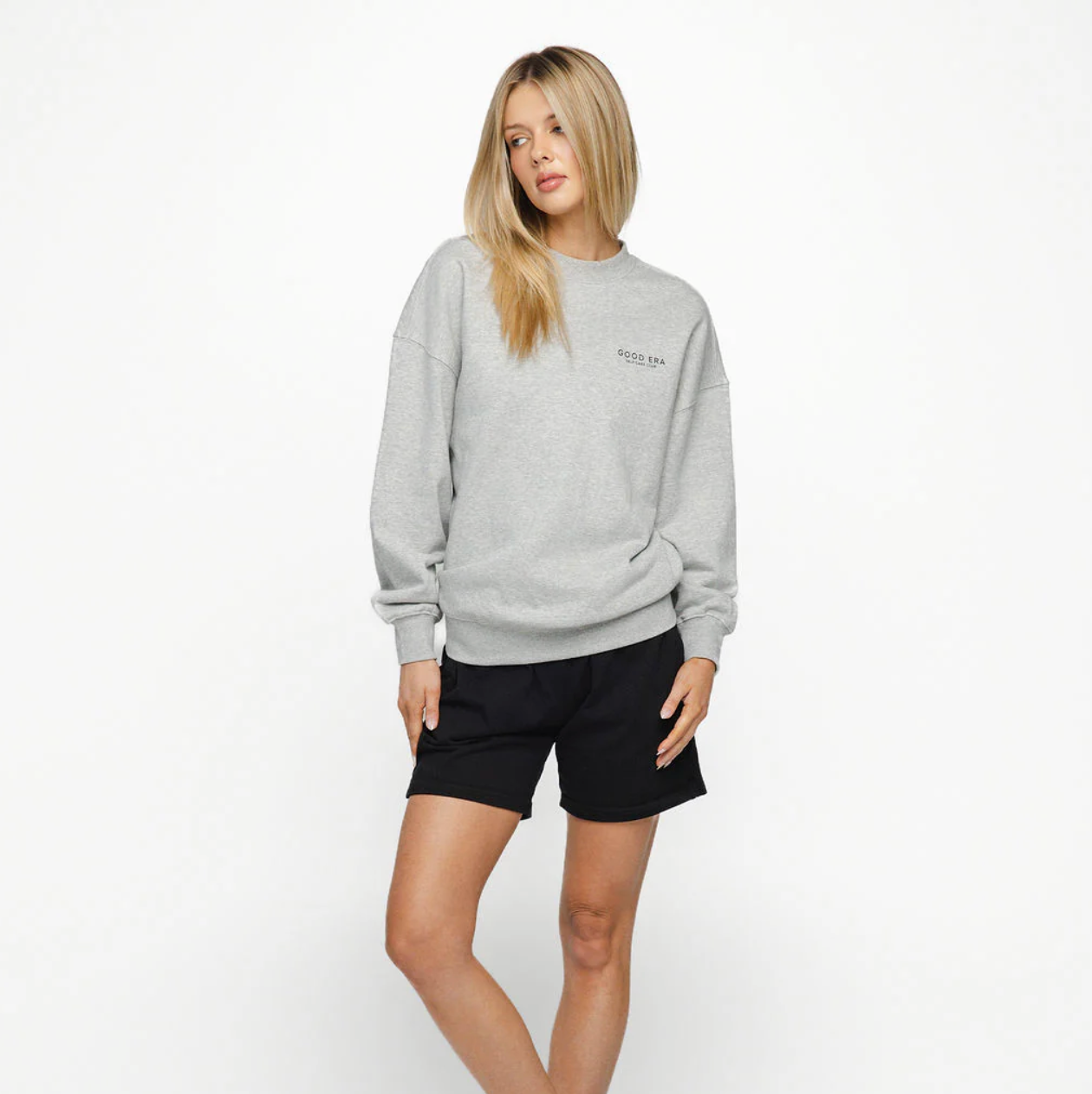 Woman wearing a gray sweatshirt and black shorts on a white background