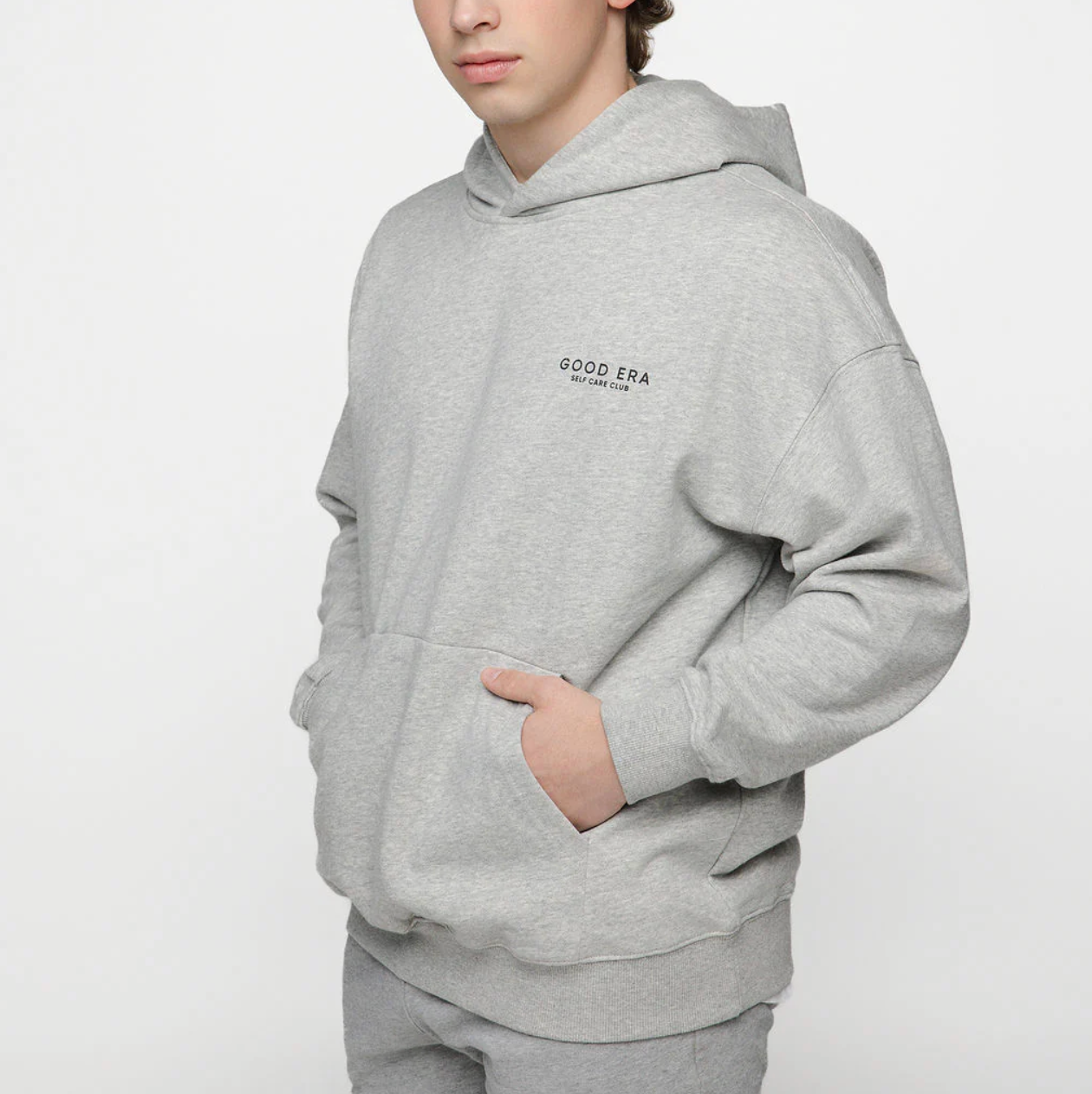 Person wearing a gray hoodie with 'Good Era' logo on a white background