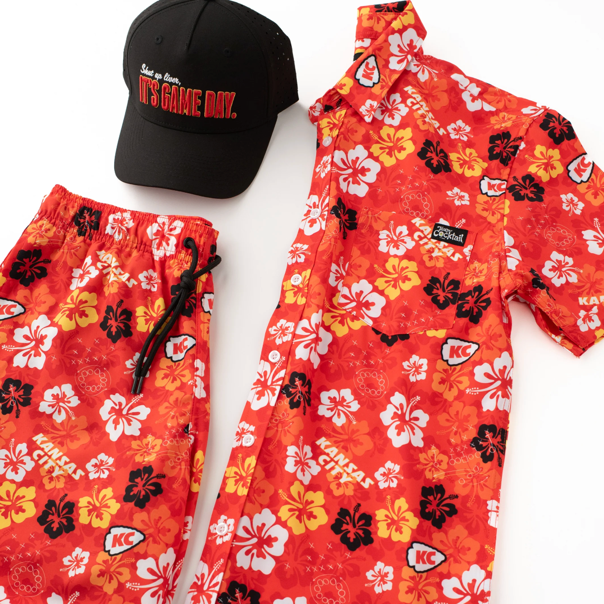 Red floral-patterned shirt, black cap, and red shorts on a white background