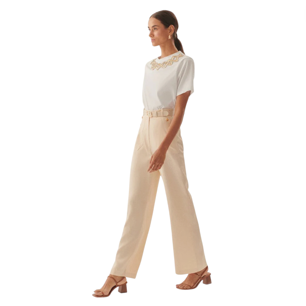 Woman wearing a white top and beige pants on a white background