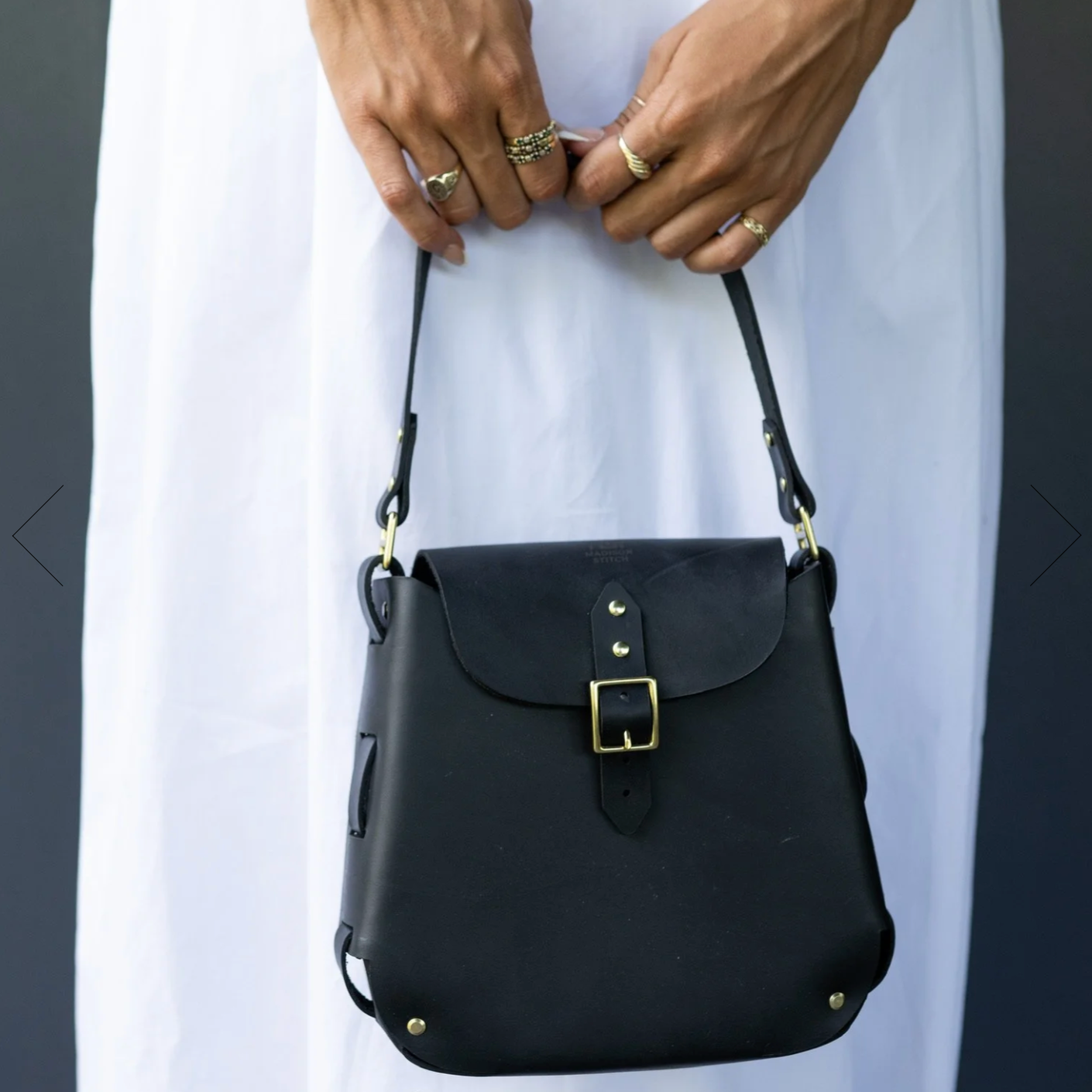 Black leather handbag held by a person with a plain background