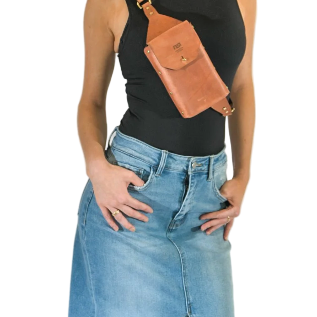 Person wearing a black top and blue jeans with a brown leather bag over one shoulder on a white background