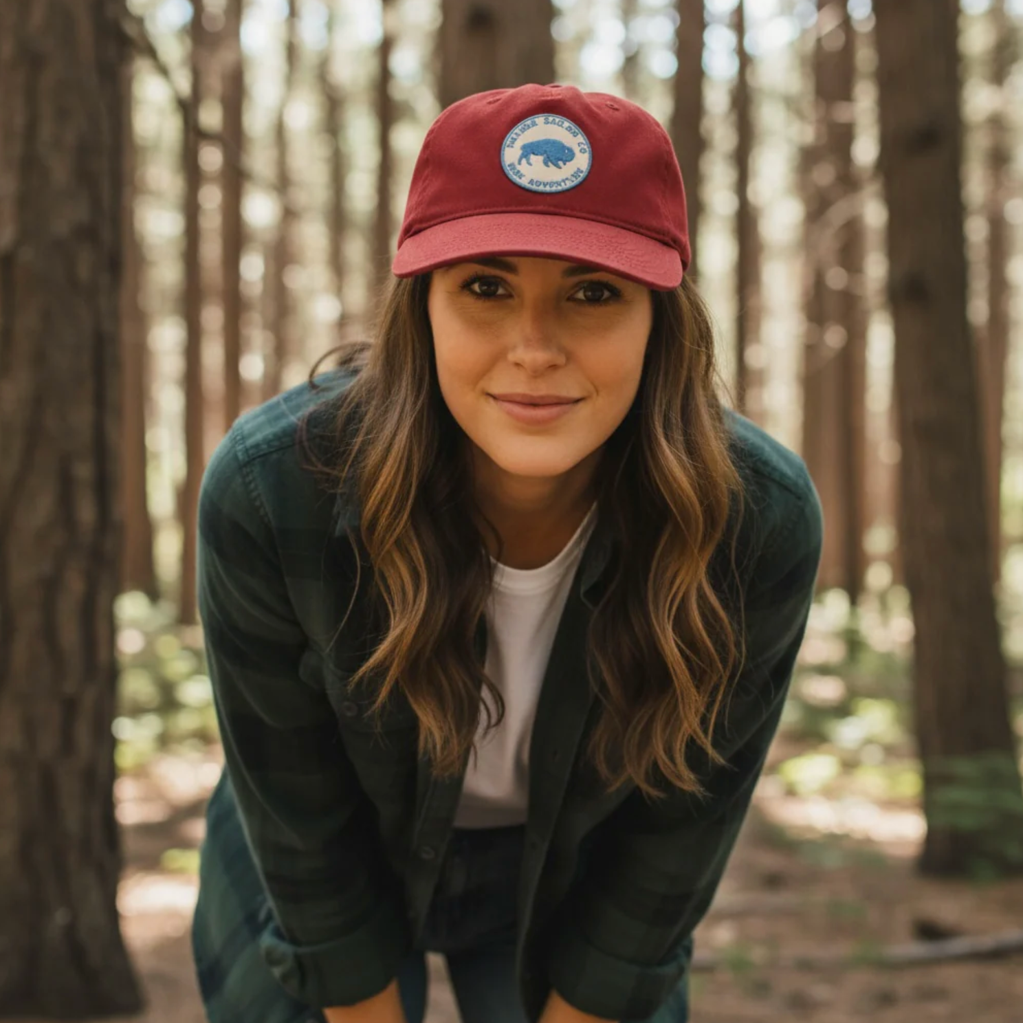 Woman wearing a red cap with a logo in a forest setting