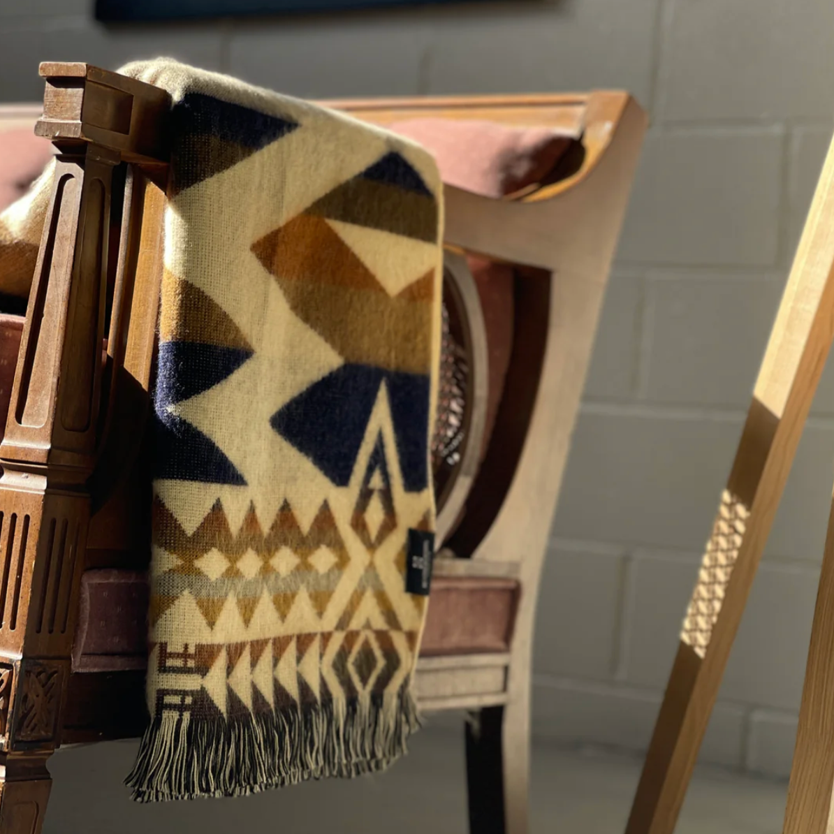 Geometric patterned throw blanket draped over a chair with a neutral background