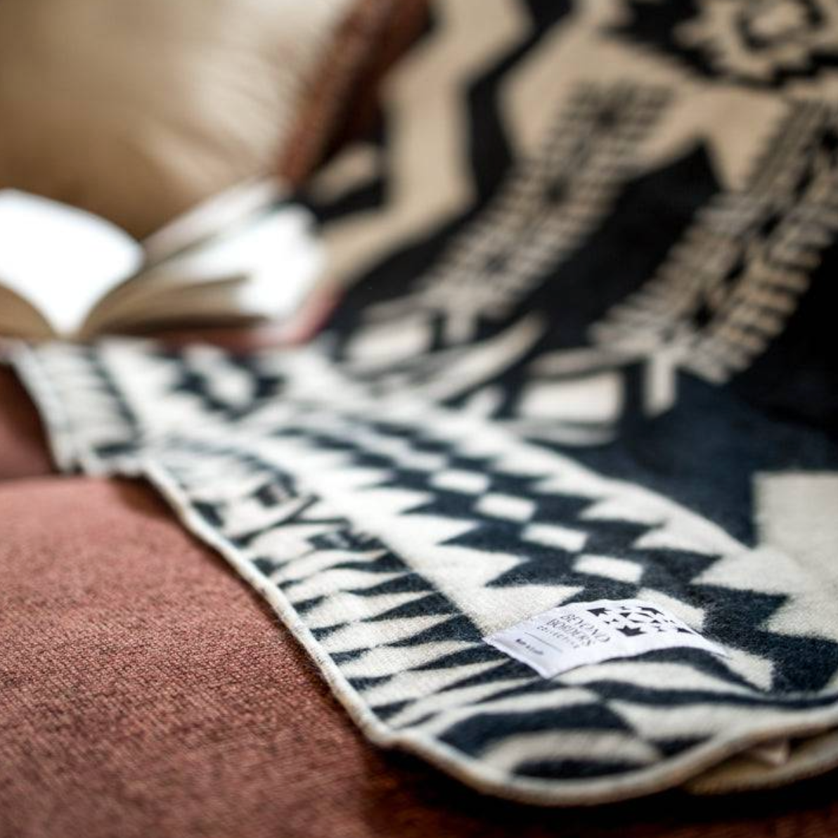 Close-up of a patterned blanket with a visible brand label on a textured surface.