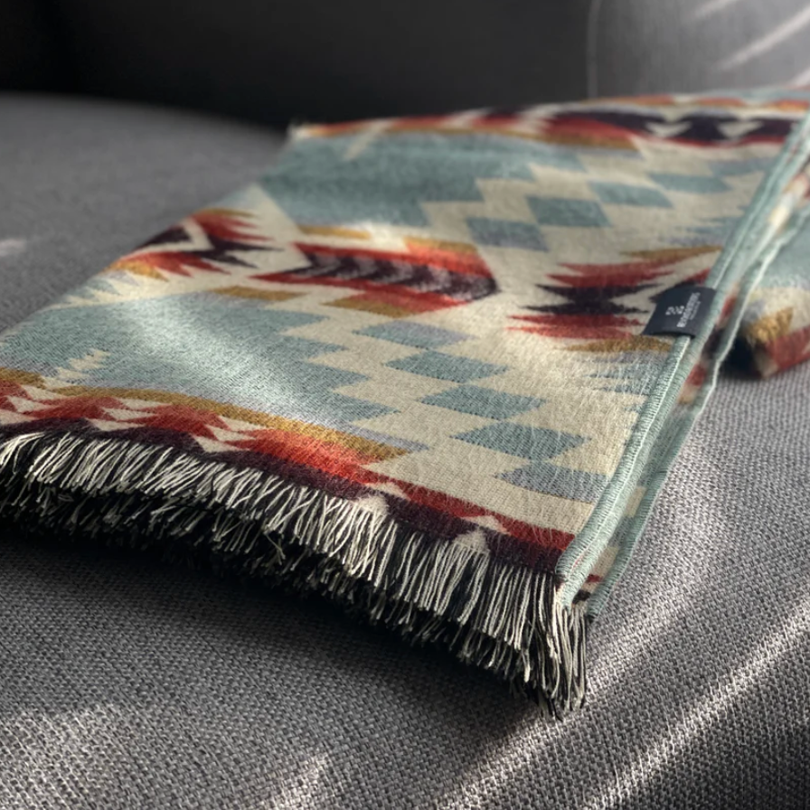 Patterned blanket with fringes on a gray surface