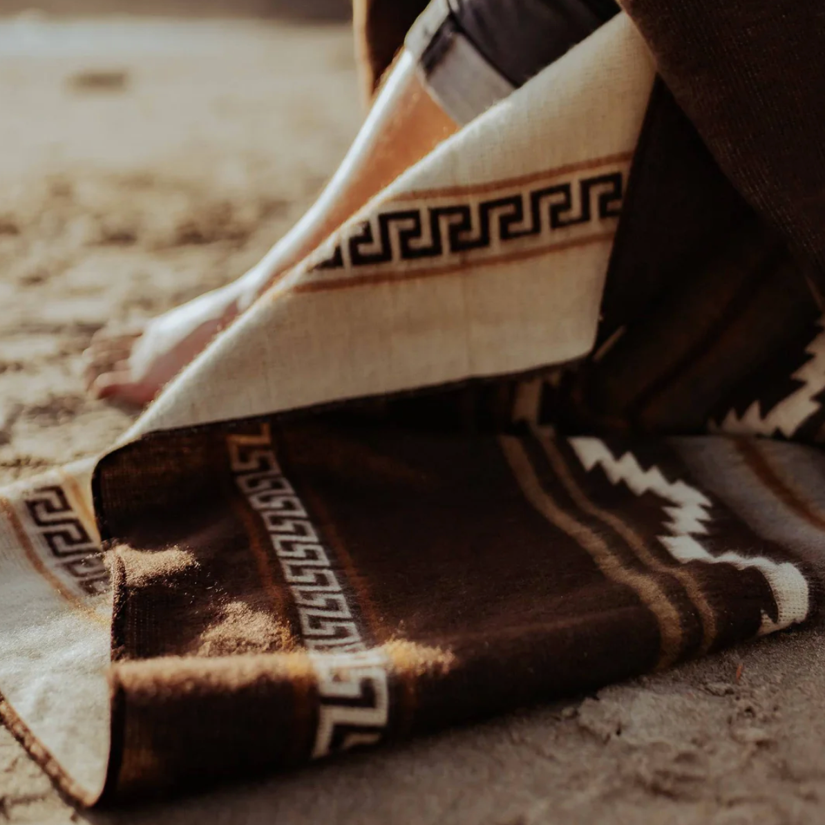 Person sitting on a patterned rug with feet visible