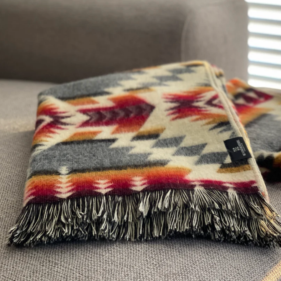 Colorful patterned blanket with fringes on a gray couch