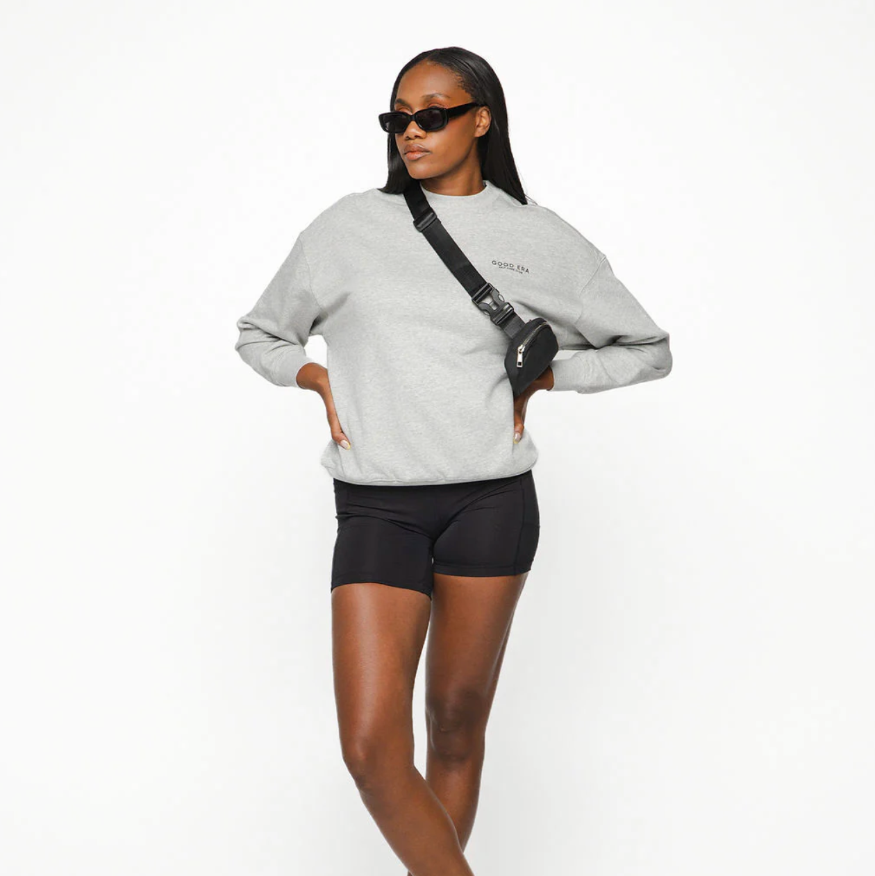 Woman wearing a gray sweatshirt and black shorts on a white background