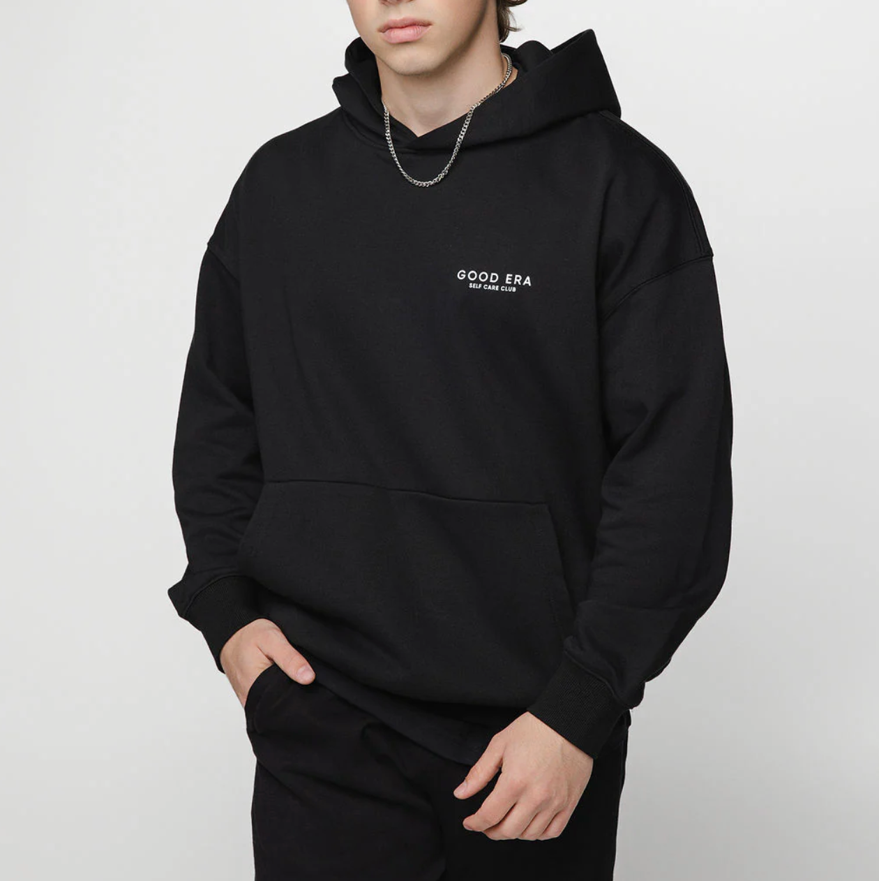 Person wearing a black hoodie with 'GOOD ERA' logo on a white background