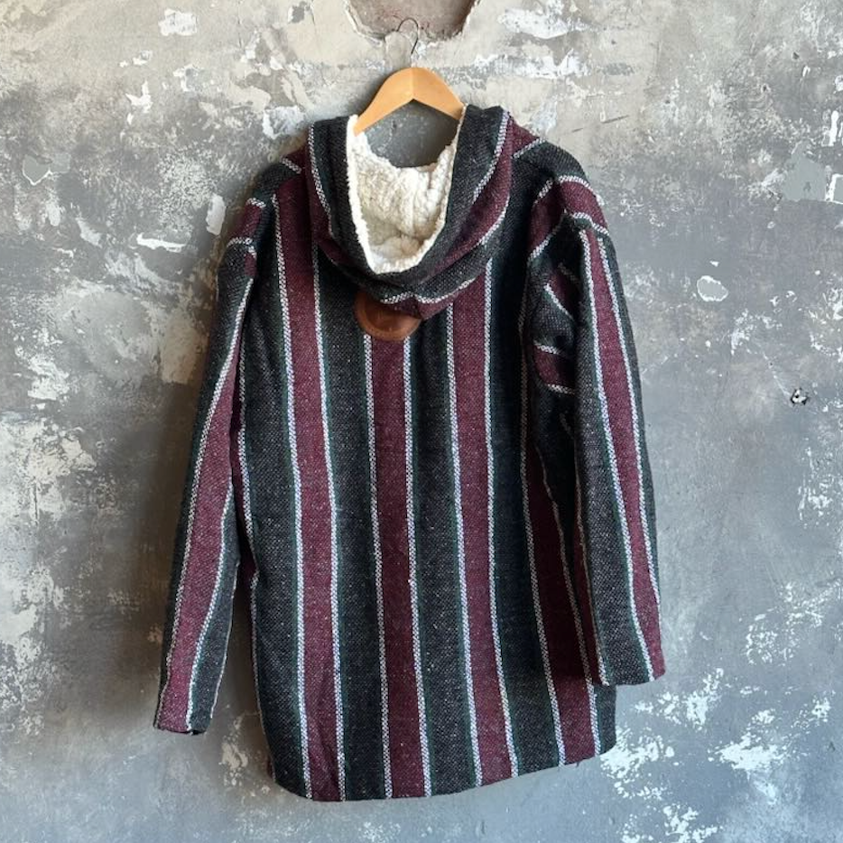Striped hoodie with a hood on a hanger against a textured gray wall