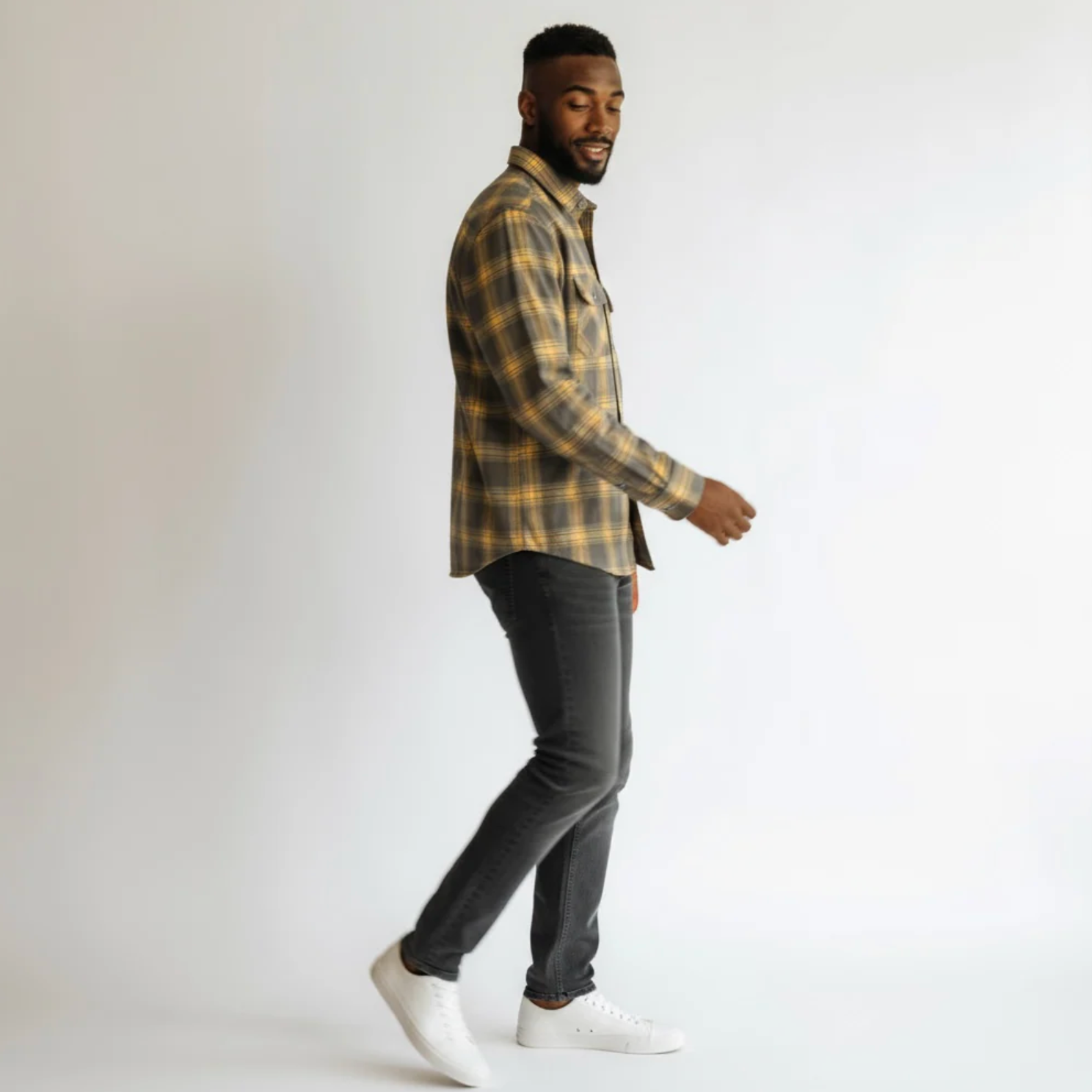 Man wearing a plaid shirt and dark pants on a white background