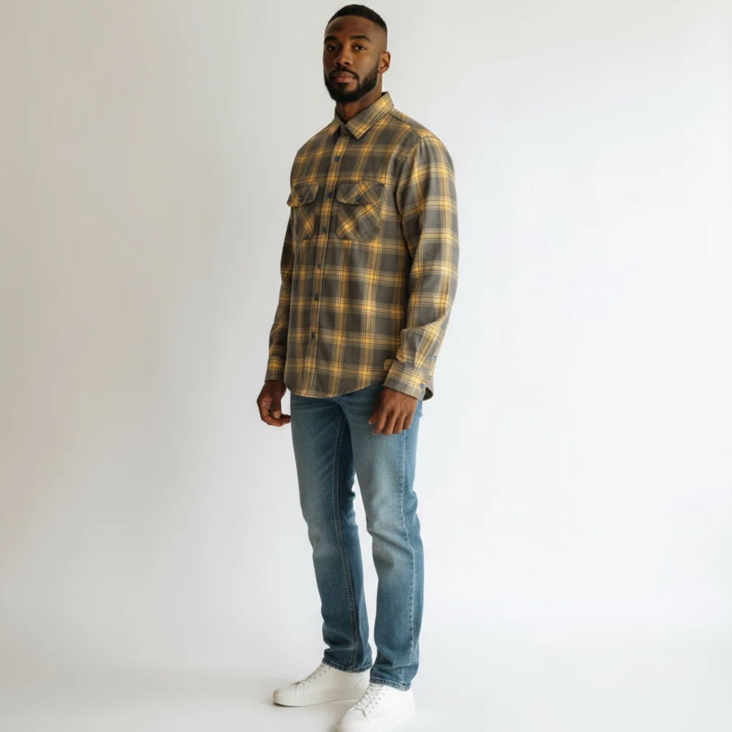 Man wearing a plaid shirt and jeans on a white background