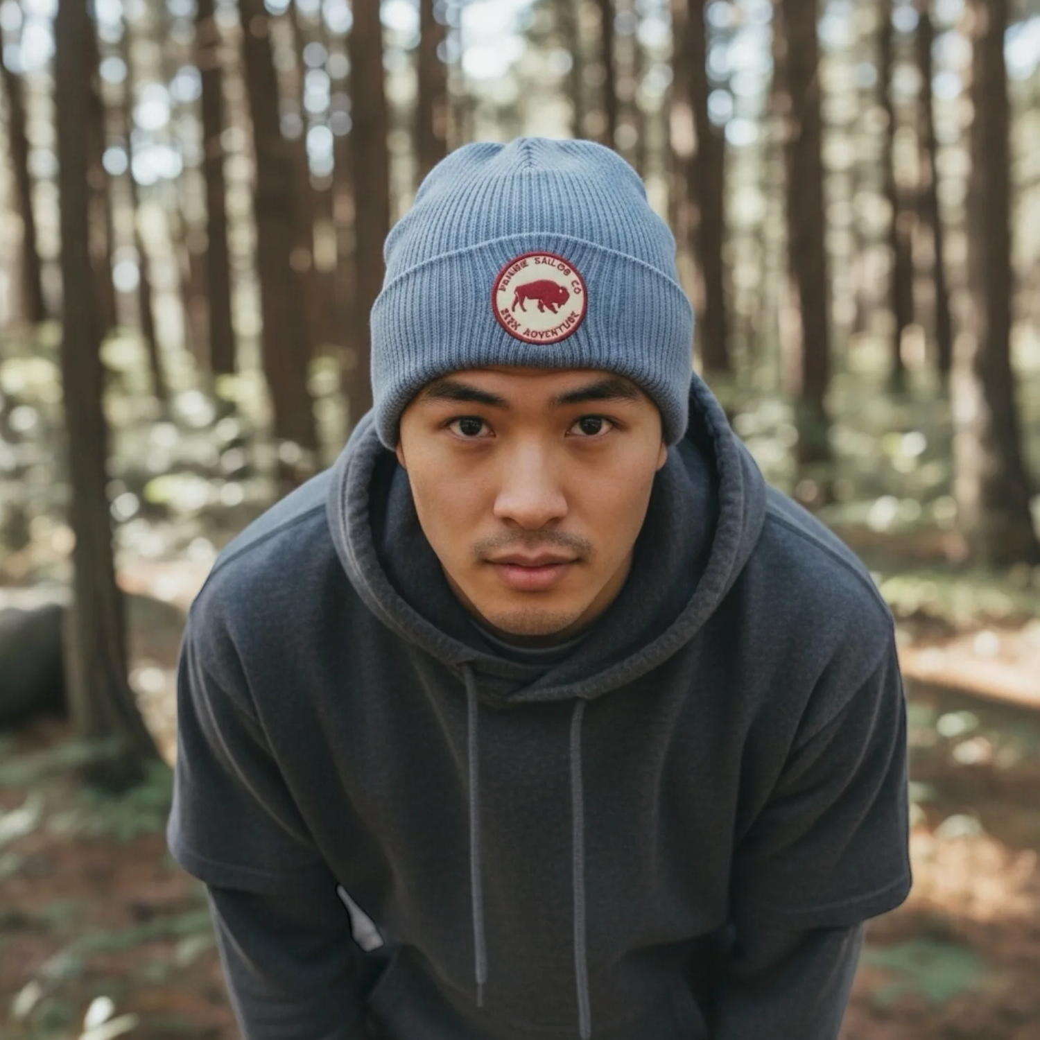 Person wearing a blue beanie with a logo in a forest setting